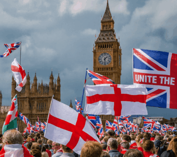 Crowd waving Union Jack and St. George’s Cross flags during Unite the Kingdom rally at Big Ben in London.